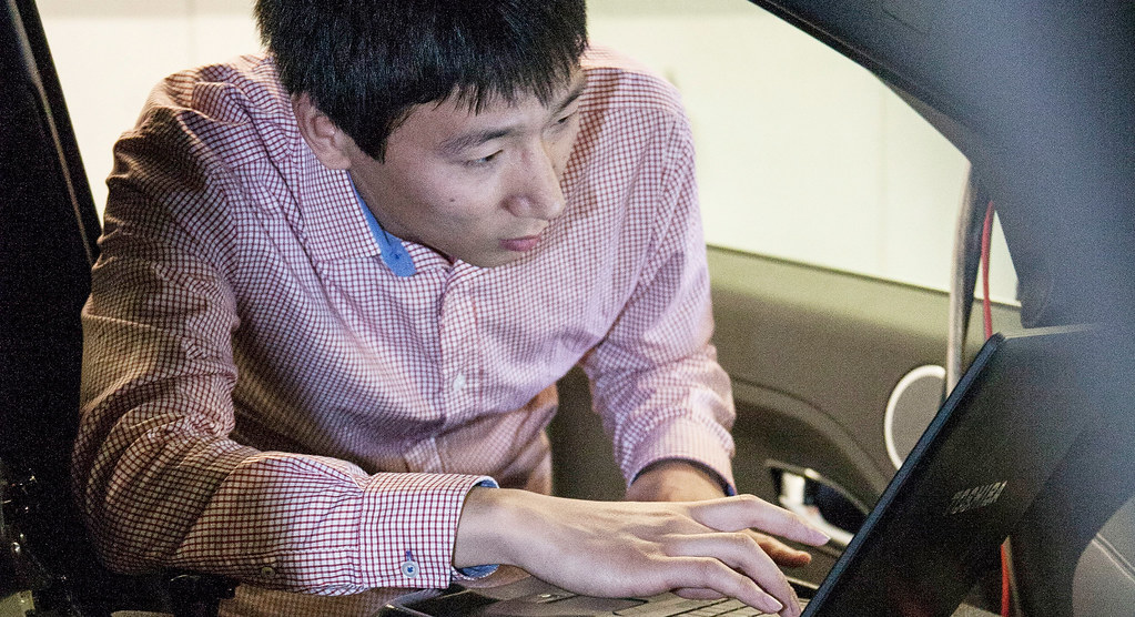 Nic looks at data on a laptop in a car within our automotive lab.