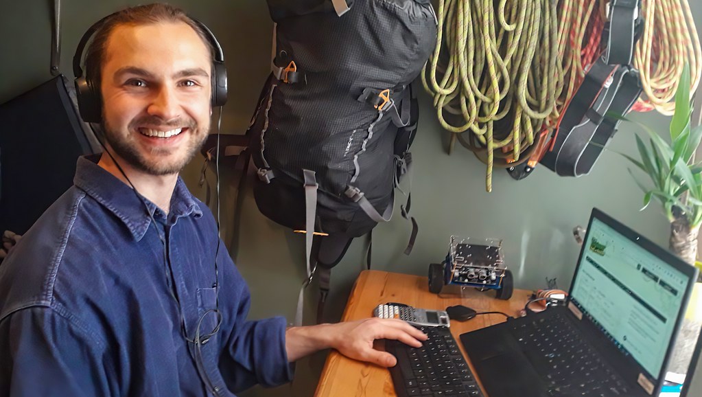 A male scientist looking to the camera and smiling whilst working at a laptop computer