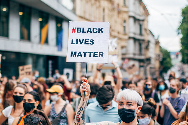 White and blond woman holding a Black Lives Matter sign at a protest march