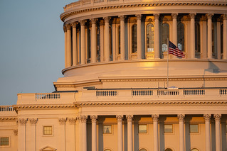 Close up sunset golden hour view of the US Capitol Building dome and columns, with the American Flag