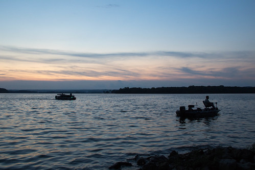 Weiss Lake by Tim and Renda, A pontoon boat cruising the lake's waters and a fisherman in a boat trolling close to the shore afte