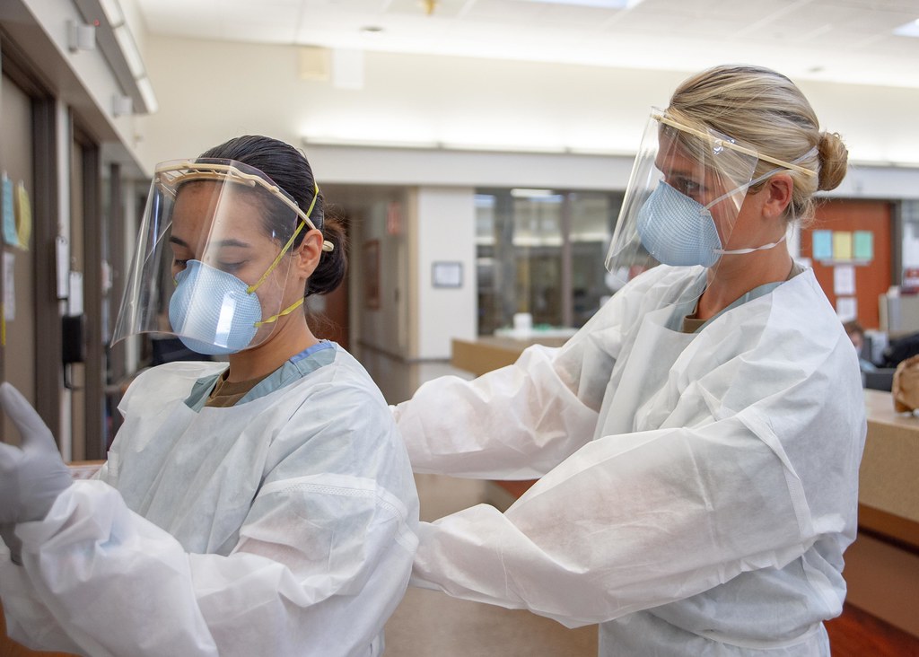 Medical personnel don PPE before entering a COVID-19-positive, non-critical patient’s room.
