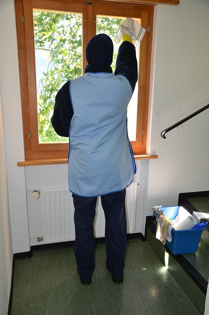 Charwoman cleaning the window in summer uniform