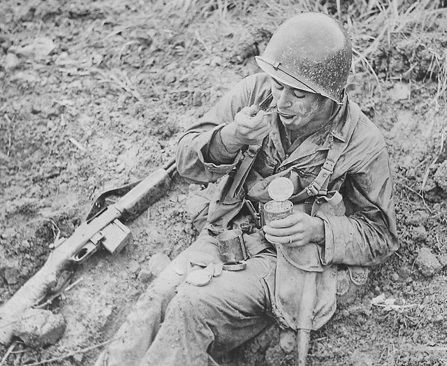 Private 1st Class Terry Paul Moore, 2nd Platoon, F Company, 184th Regiment, 7th Division, United States Marine Corps, at lunch in Okinawa.  eating  field ration  (C ration) May 22nd 1945.