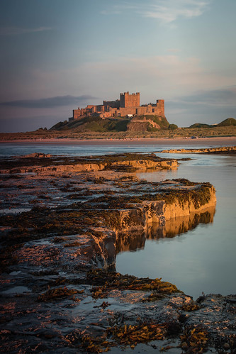 bamburgh castle northumbria beach rocks seaweed sand rock sea waves yellow reflection sky clouds sunset dunes water