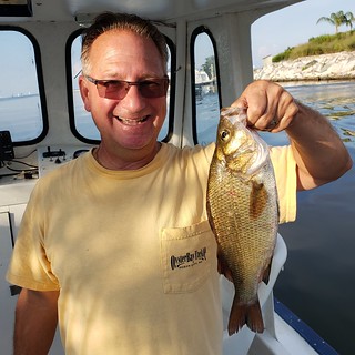 Photo of man in a boat holding a white perch