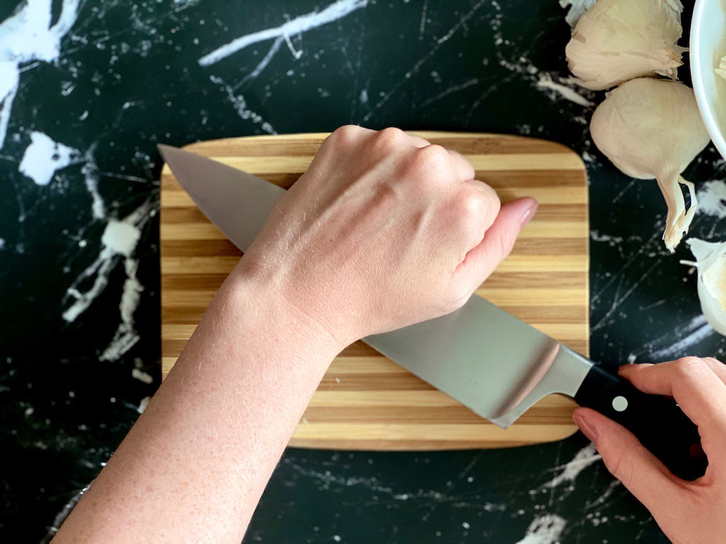 Firmly grip the handle with one hand. With the heel of the other hand, firmly press down on the flat side of the knife.