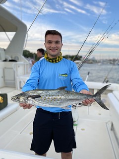 Photo of man on a boat holding a Spanish mackerel