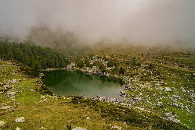 Mountain pond reflects the surrounding nature shrouded in morning fog