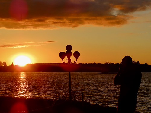 Photographing the Sunset by ironmike9, My son-in-law taking a photo of the sun setting over the Saint Lawrence River. The tower of the pow