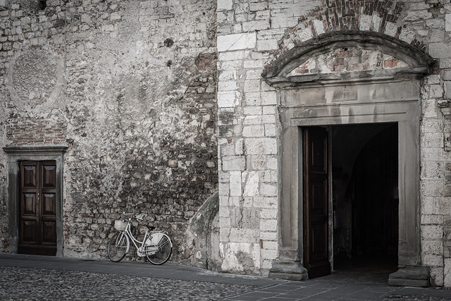 Bicycle leaning against the brick wall of a church with the door open