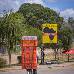 Bicyclist loaded with fresh bread approaching the Equator sign in Nanyuki, Kenya, East Africa
