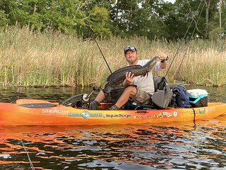 Photo of man holding a northern snakehead in a kayak