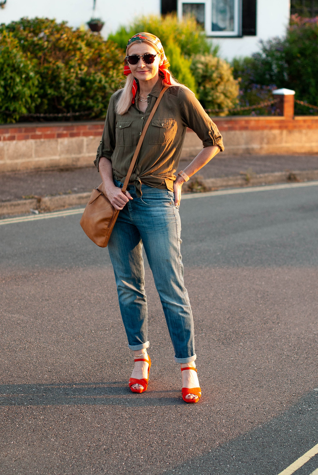 70s Head Scarves and Boyfriend Jeans Older Than Millie Bobby Brown | Not Dressed As Lamb, over 40 style (Catherine is wearing a green and orange patterned headscarf, a loose olive green shirt, boyfriend jeans and strappy orange sandals in a street-style photo)