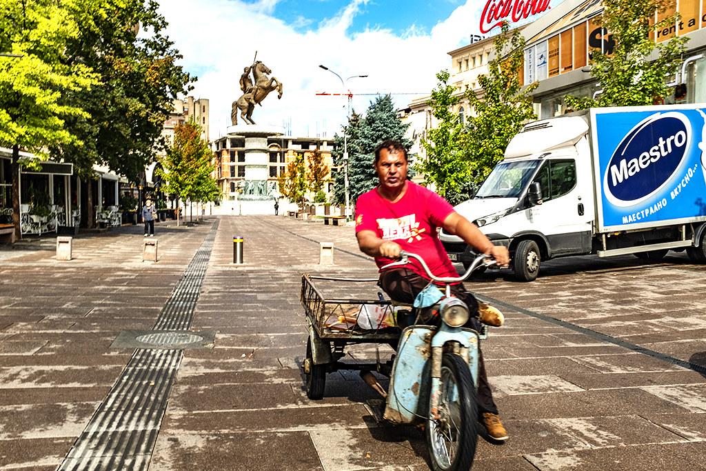 Man on three-wheeled truck with Alexander the Great Statue in background on 9-26-20--Skopje