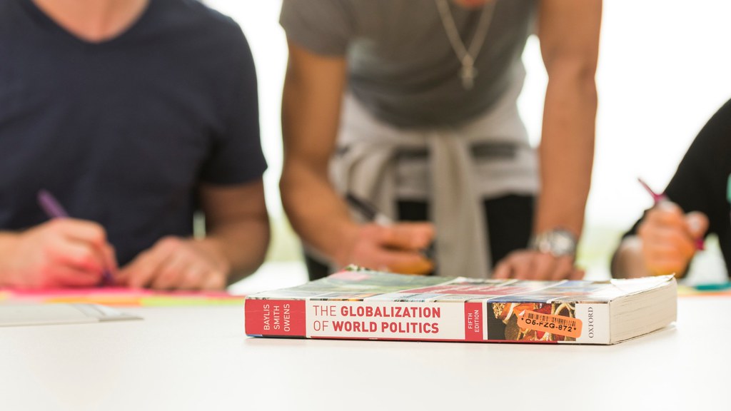 A book titled 'The Globalization of World Politics' ona. table with people sat around it.