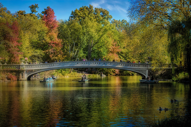 View of the Bow Bridge and boaters on a The Lake on a warm fall day in Central Park, Manhattan