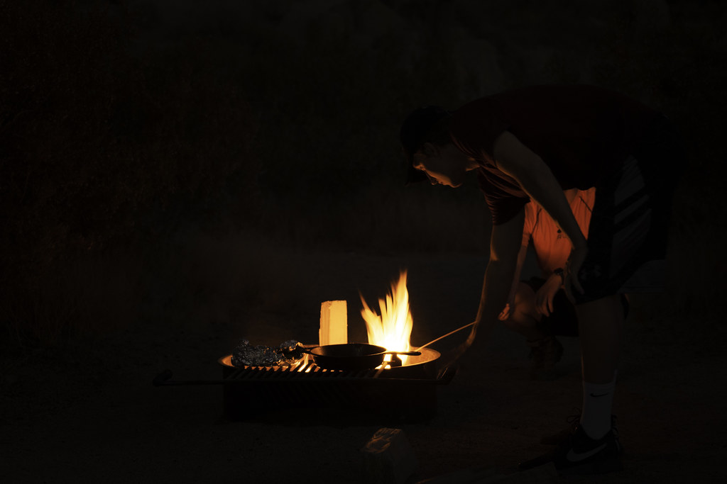 Cooking over a campfire in Jumbo Rocks Campground - a man in a black shirt is cooking on a fire