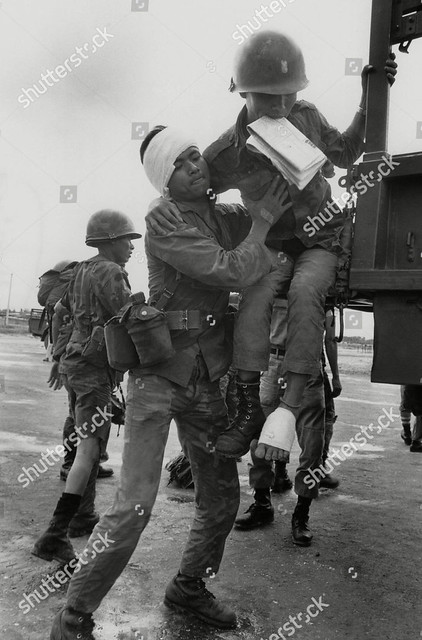 Tây Ninh - Vietnamese Airborne soldier suffering from a headwound lifts a more seriously wounded buddy onto a waiting truck