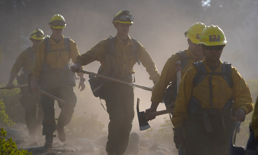 U.S. Marines and Sailors hike to recover fire hoses while conducting wildland firefighting operation