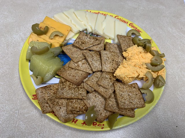Cheese and Crackers with pickles and olives served on a classy Curious George plate