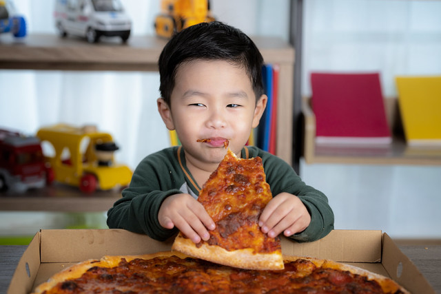 Asian boy eating pizza