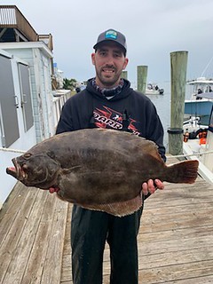 Photo of man on a dock holding a flounder