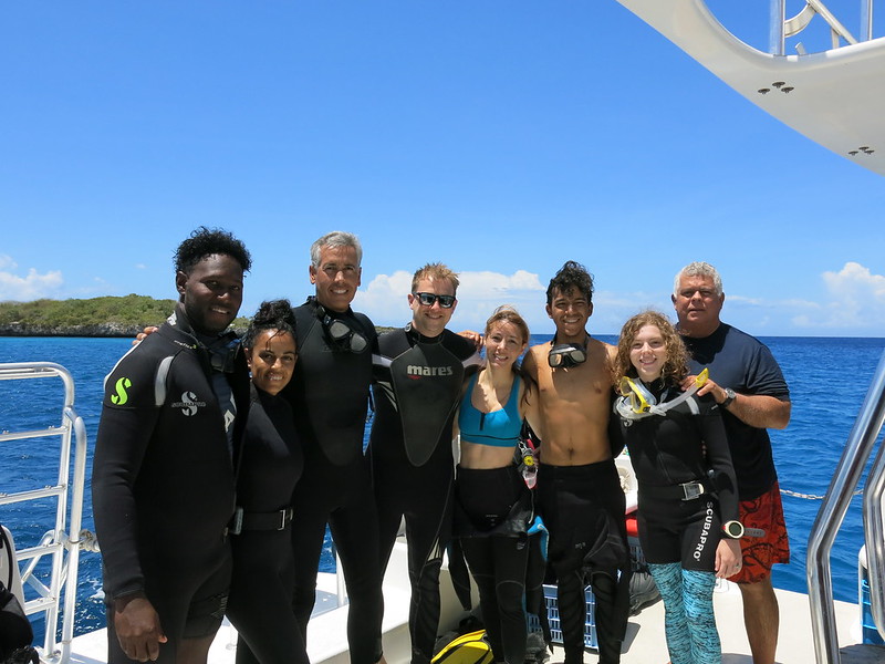Reef-World's Director JJ Harvey taking part in Green Fins Dominican Republic. Photo shows JJ and a group of divers standing on a boat deck in front of a blue ocean