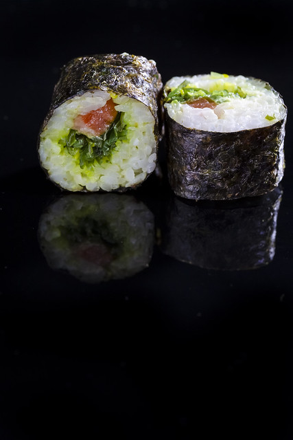 Japanese Cuisine. Macro Shoot of Two Traditional Sushi Rolls With Salmon and Laminaria Together on Black Surface.