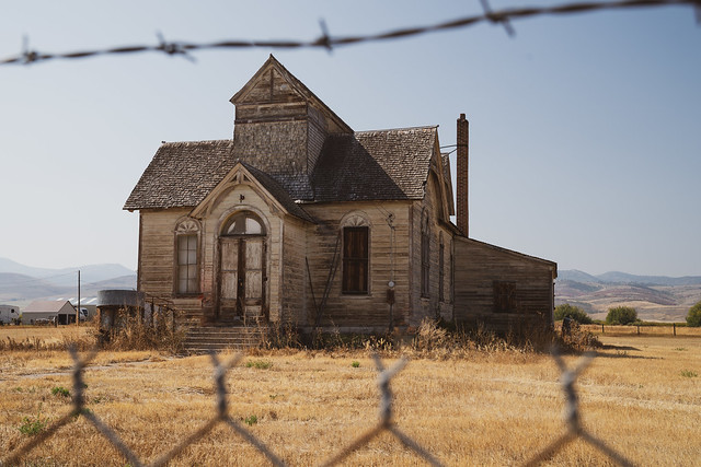 Old, abandoned LDS mormon church, framed by barbed wire, in Ovid, Idaho
