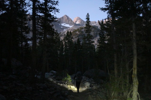 1735 Mount Gayley and Mount Sill shine with alpenglow as we hike in the darkness of the forest down below before dawn