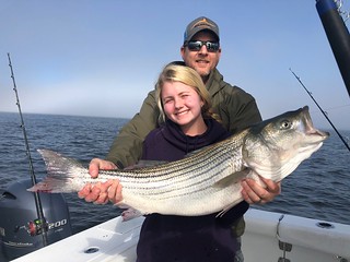  Photo of man and daughter holding a striped bass