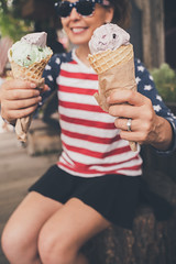 Lifestyle portrait of a young woman wearing Americana clothing, enjoying a waffle cone. Focus on ice cream cone, woman intentionally blurred