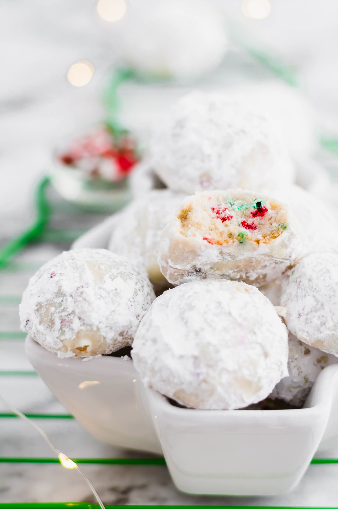 Tender, melt in your mouth Christmas Snowball Cookies are the perfect addition to your baking list this season. Super festive and fun.