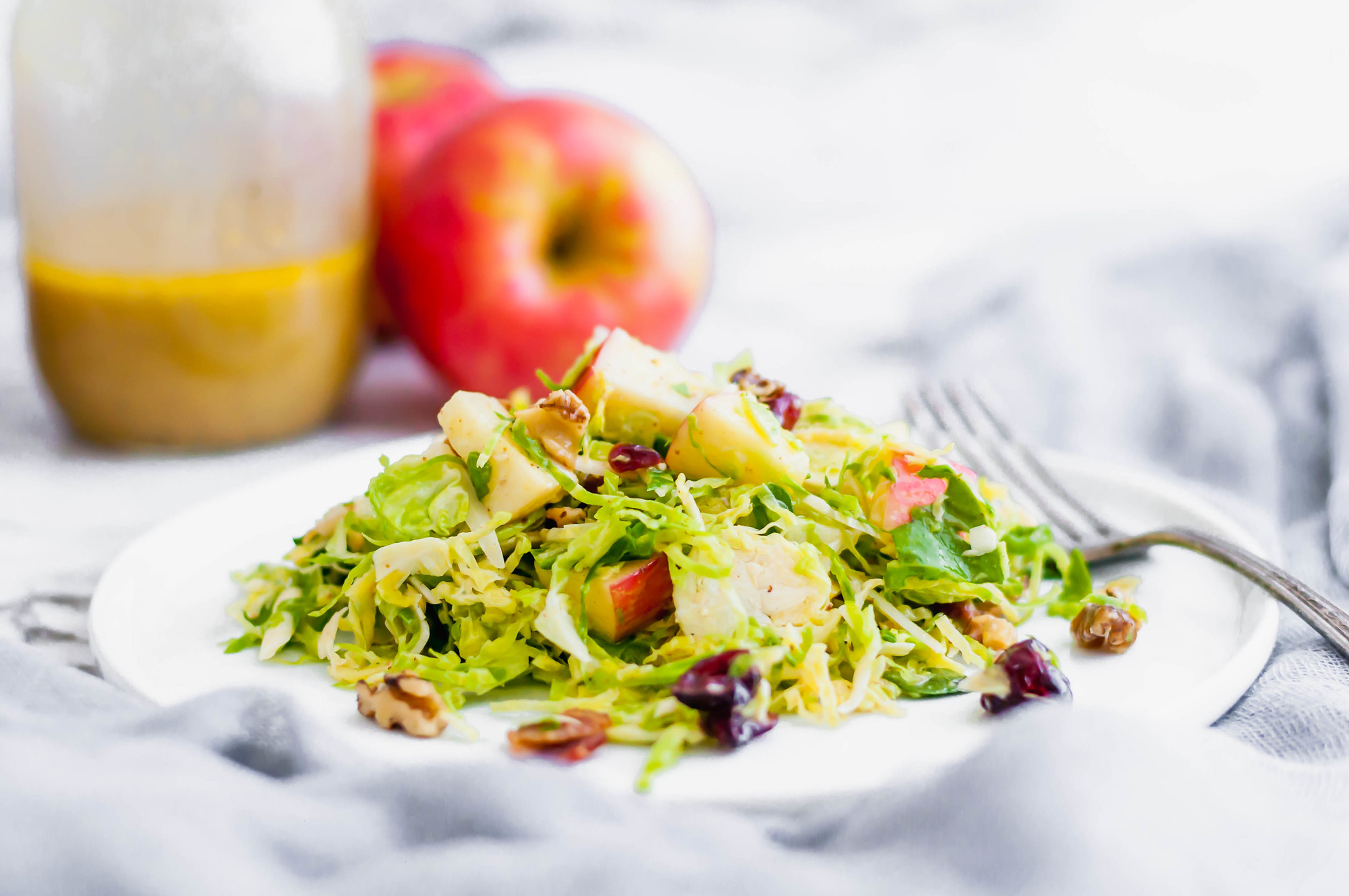 This Shaved Brussels Sprouts Salad is the perfect addition to your Thanksgiving table. It's bringing all the fresh fall vibes. Full of fresh shaved brussels sprouts, honeycrisp apples, craisins, sharp cheddar cheese, toasted walnuts and the most delicious honey mustard vinaigrette. Prepare the ingredients ahead of time and toss together at the last minute for a stress free holiday dinner.