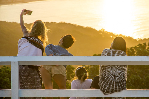 girls selfi smartphone rear byron bay lighthouse famous sunset four people short shorts