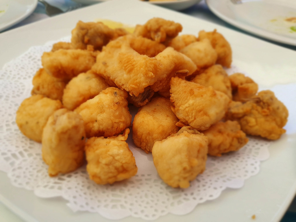 golden small deep fried pieces of dogfish, on a white plate.