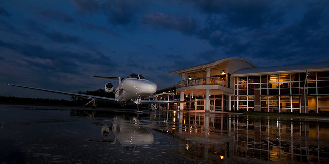 A plane on the tarmac outside Auburn University Regional Airport at night.