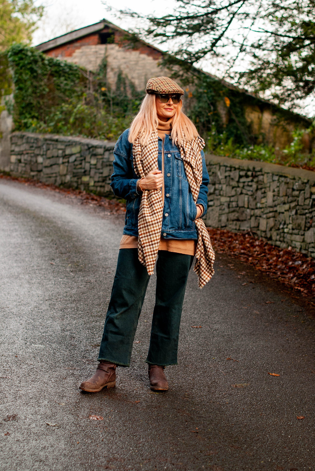 Why It's Perfectly Okay to Wear Unflattering Outfits (Catherine Summers of Not Dressed As Lamb is wearing a tweed flat cap, a woollen tweed scarf, oversized denim jacket, wide leg dark green jeans, camel roll neck sweater and muddy brown boots)
