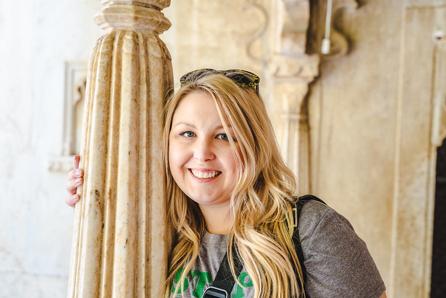 Smiling blonde woman tourist poses near a column in Udaipur, India