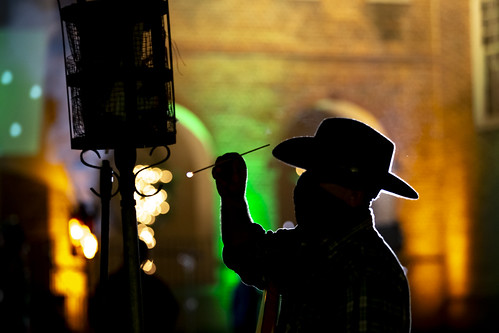 A staff member lights one of the cressets in the Wren Courtyard.