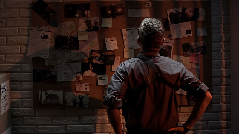 A police officer looking at a wall of evidence