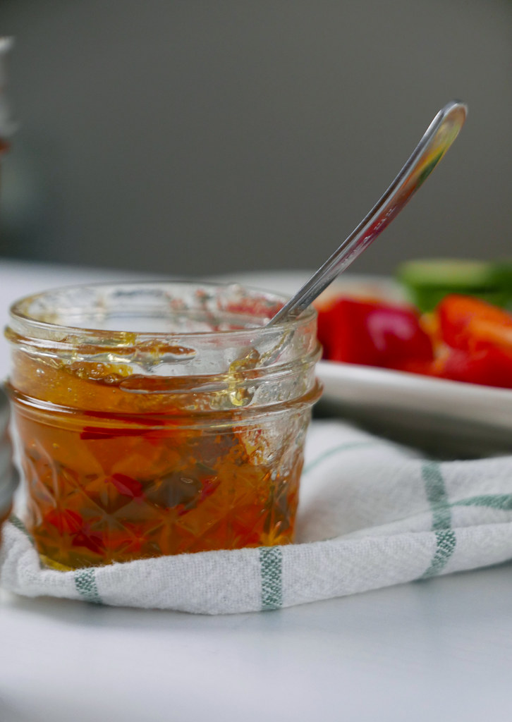 An opened jar of hot pepper jelly sitting on a cloth. 