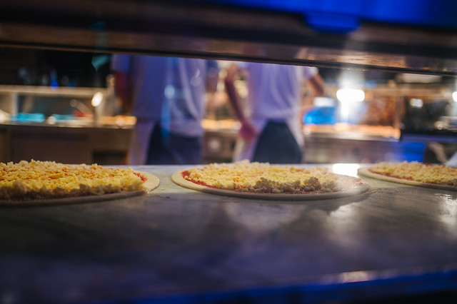 Raw pizza on a counter and chefs in a blurry background