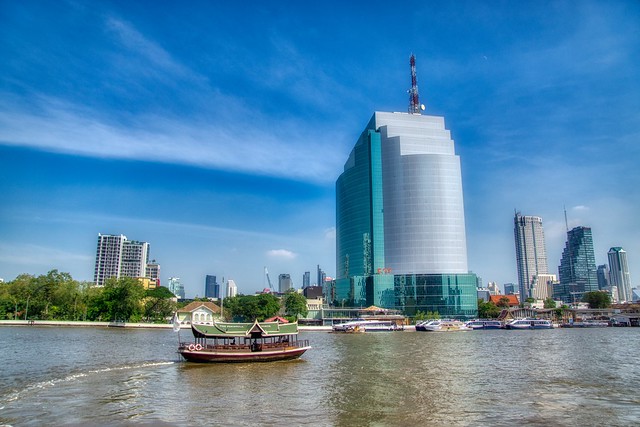 Chao Phraya river with shuttle boat of the Peninsula hotel and Cat Telecom building in Bangkok, Thailand