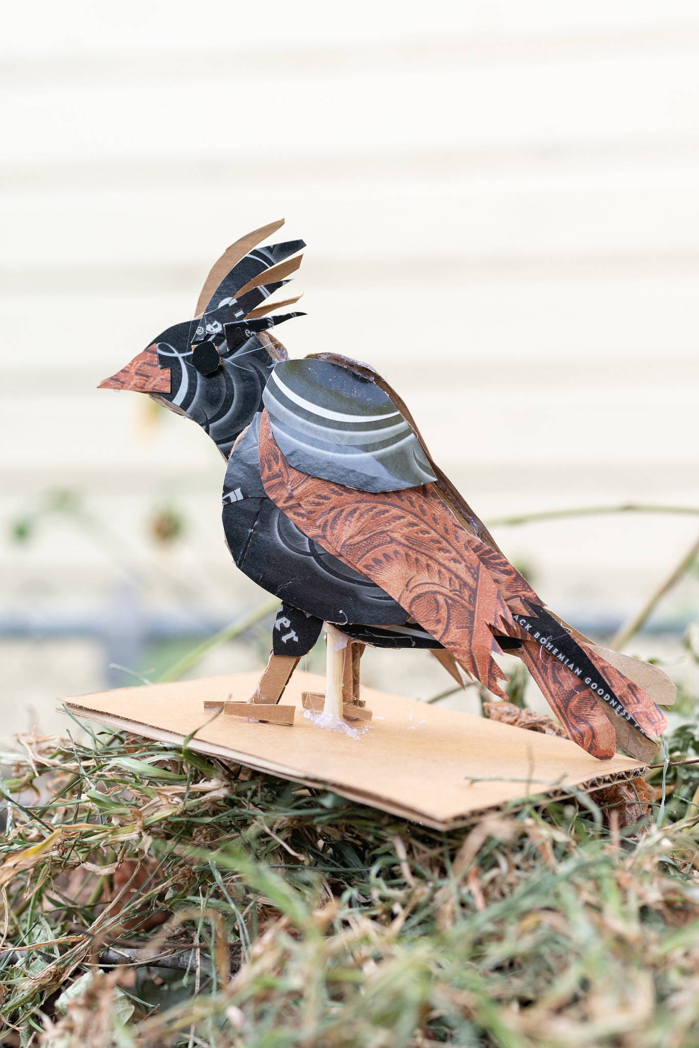 Sculpture of a crested bird made of black and brown cardboard