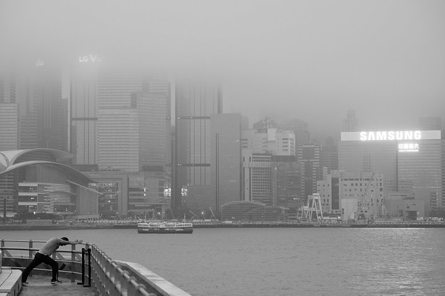 Morning exercises with a foggy view over Victoria Harbor towards Hong Kong Island, Tsim Sha Tsui, Hongkong - Jan' 2018