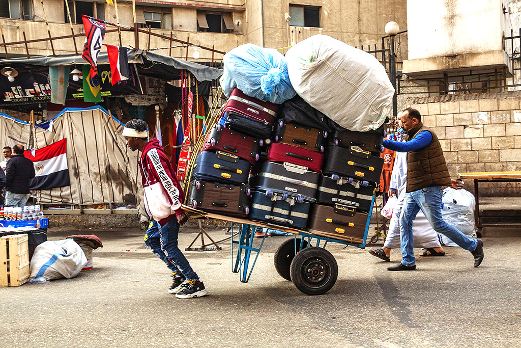 Young black man pulling cart loaded with suitcases on 1-8-21--Cairo