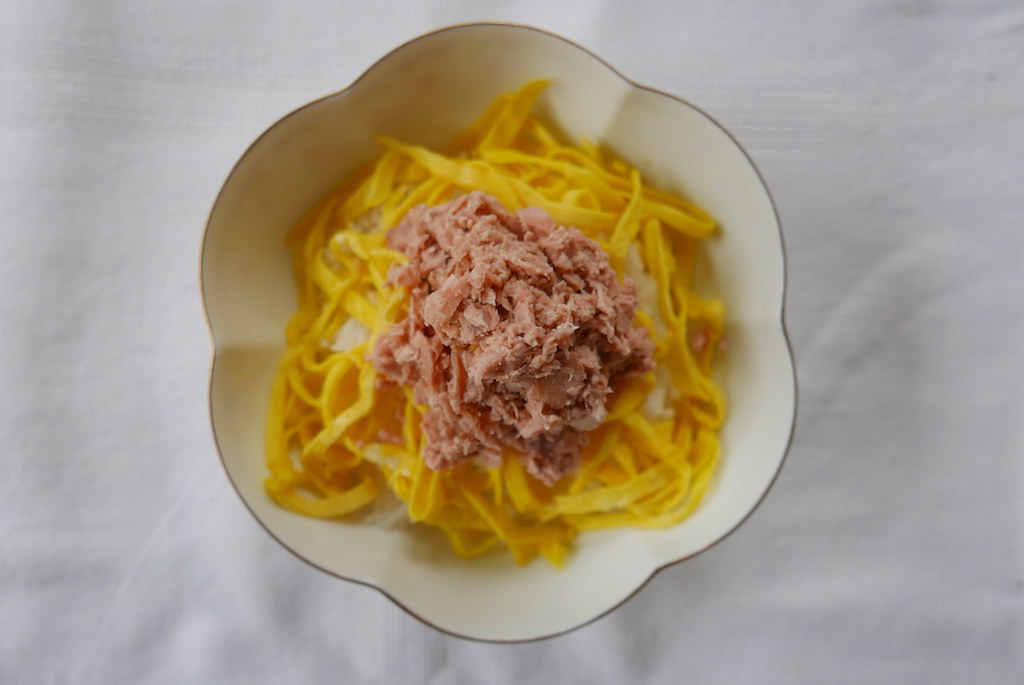 A ball of shredded tuna on top of egg and rice. 