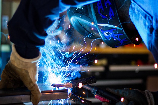 A man doing welding in garage making spark